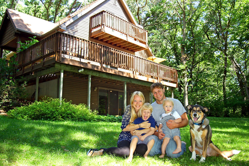 Family sitting in front of vacation home cabin.