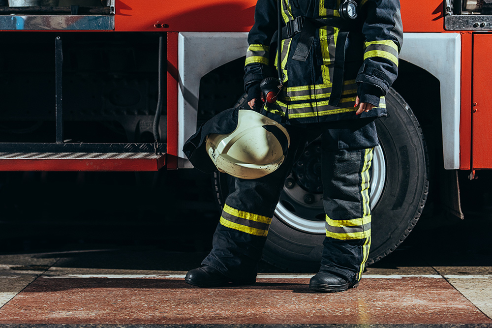 Photo of a firefighter standing in front of a fire truck