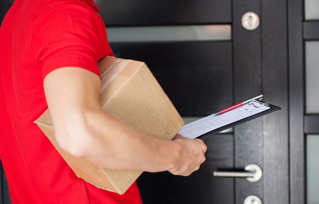 A deliveryman standing in front of a door with a video doorbell