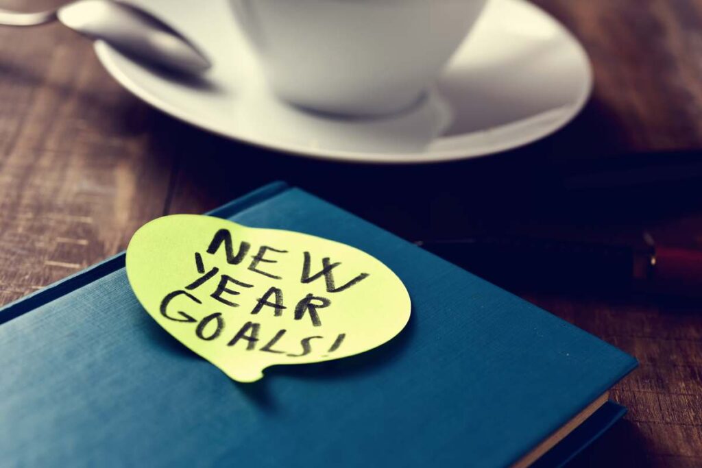 Notebook with a sticky note that says "New Years Goals" on it