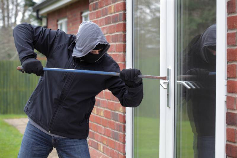 A burglar attempts to break into a home with a crowbar