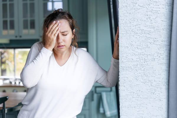 A woman suffering from carbon monoxide exposure holding her head and looking dizzy